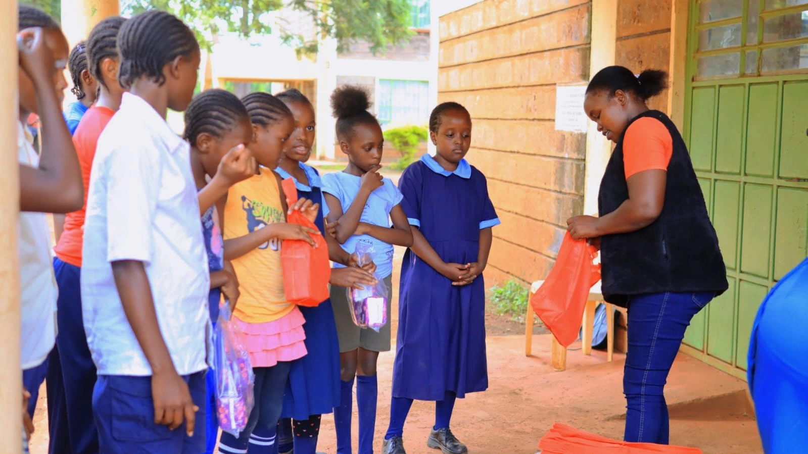 Students in school uniforms receiving sanitary towel donations